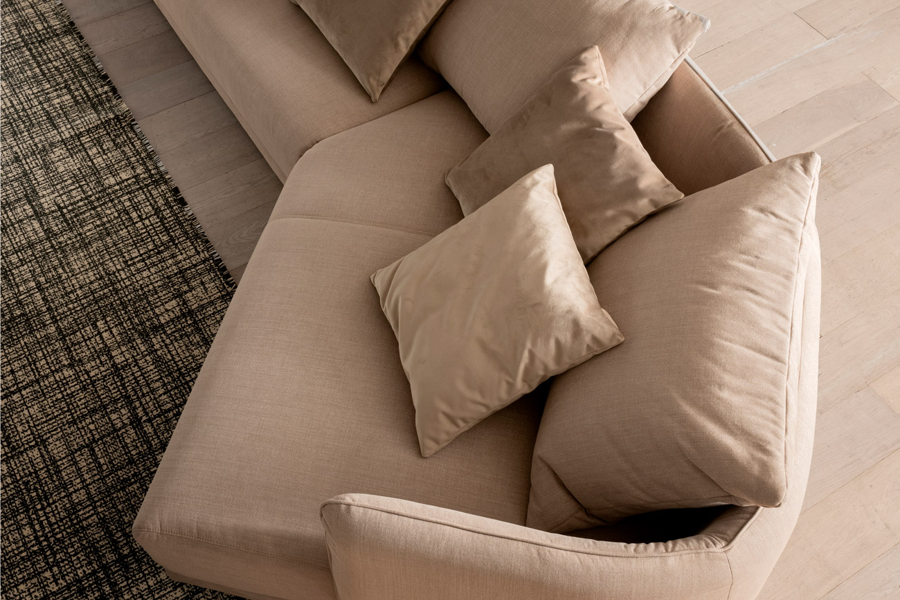 Wohnambiente mit einer Sofakombination des Modells New York mit Stoffbezug und Wurfkissen