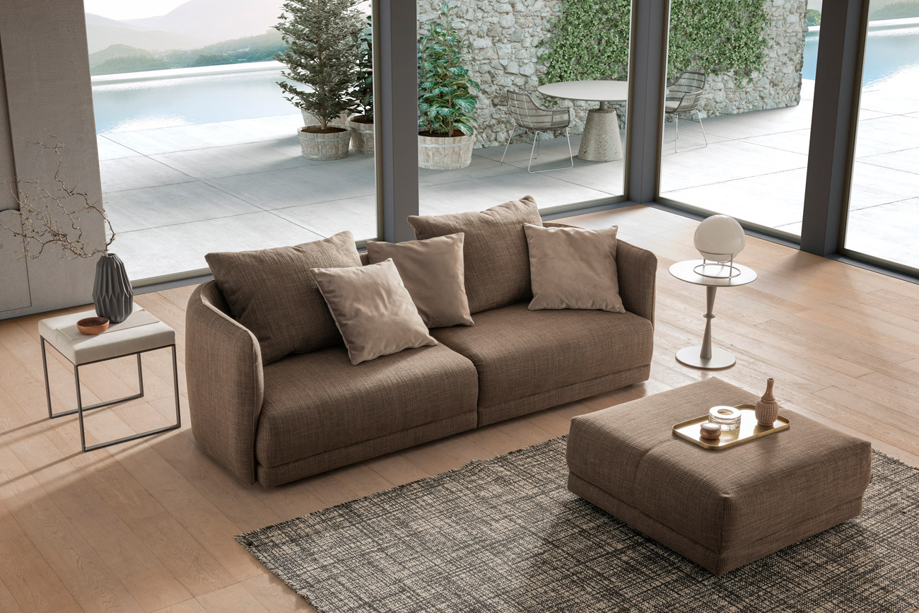 Wohnambiente mit einer Sofakombination des Modells New York mit Stoffbezug, Wurfkissen und mattschwarzen Füssen