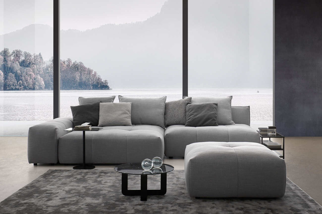 Sofakombination des Modells Palace mit grauem Stoffbezug, Wurfkissen, Center Leg, One Blade X, Lowboard und Teppich Sense