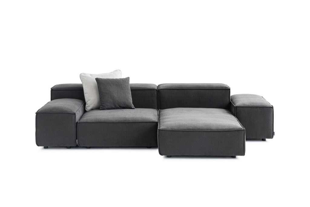 Sofakombination des Modells Puzzle mit grauem Stoffbezug, Wurfkissen und schwarzen Kunststoffgleitern