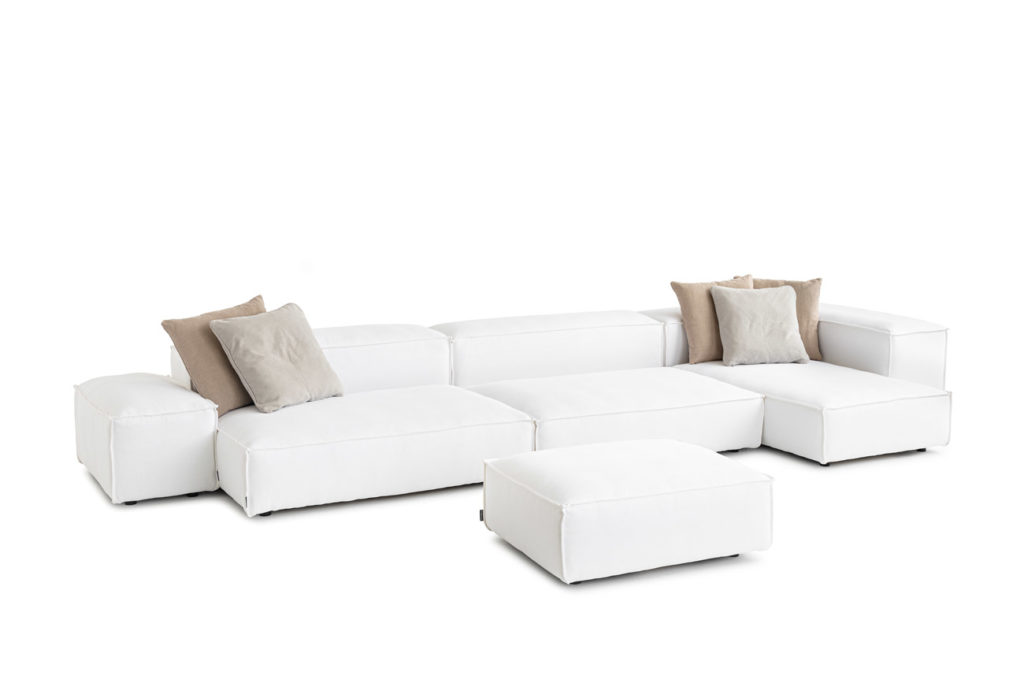 Sofakombination des Modells Puzzle mit weissem Stoffbezug, Wurfkissen und schwarzen Kunststoffgleitern
