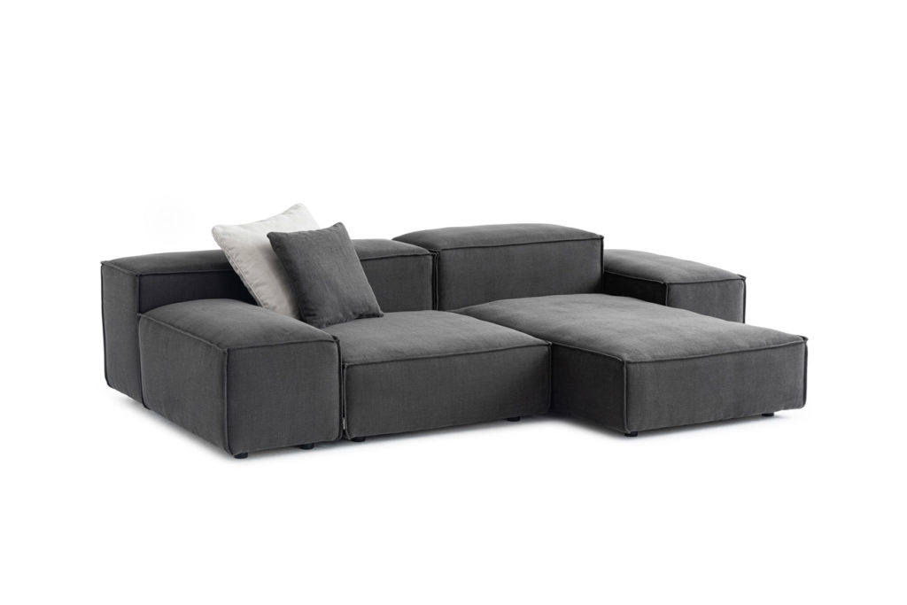 Sofakombination des Modells Puzzle mit grauem Stoffbezug, Wurfkissen und schwarzen Kunststoffgleitern