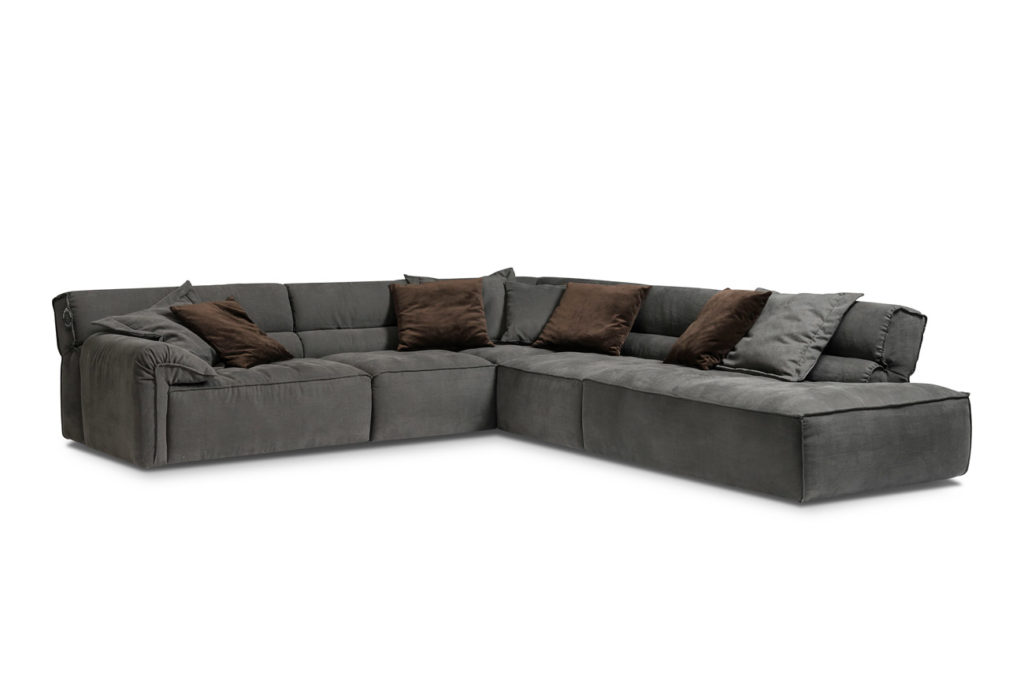 Sofakombination des Modells Vola mit grauem Stoffbezug, Flatterkissen, Wurfkissen und schwarzen Kunststoffgleitern
